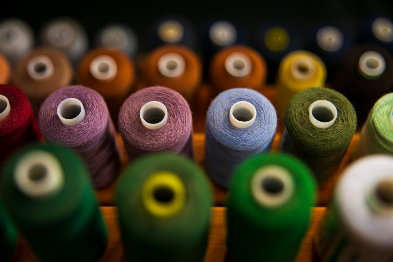 Colorful sewing thread spools arranged in rows, showcasing vibrant hues.