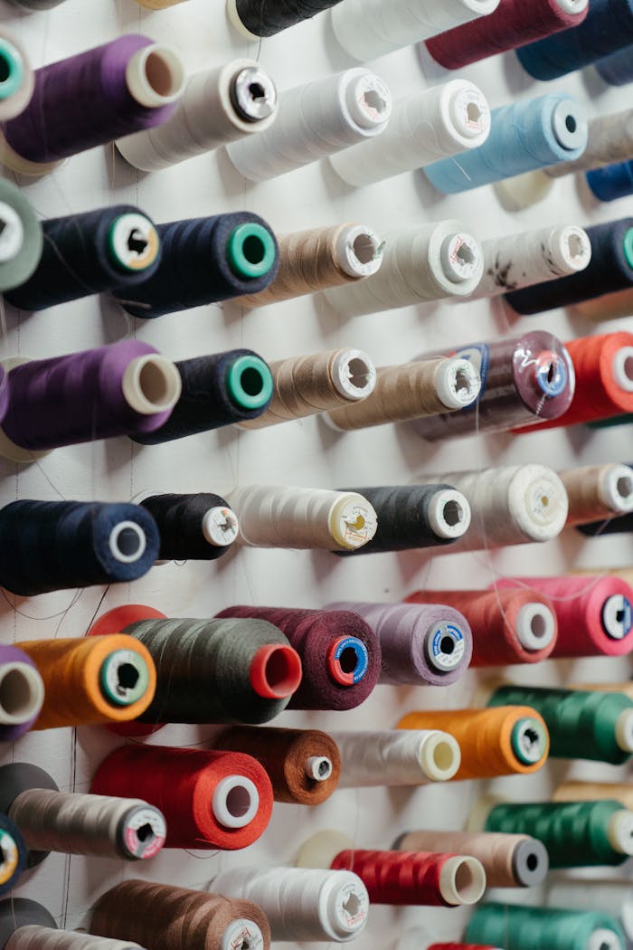 A variety of spools of thread neatly arranged in rows, showcasing vibrant colors.