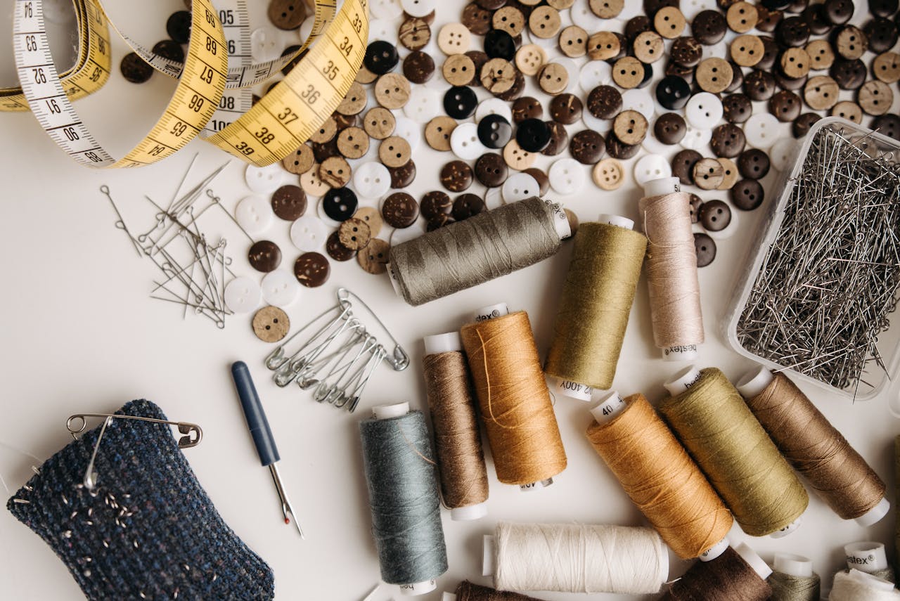 Artistic flat lay of sewing tools including threads, buttons, and measuring tape.